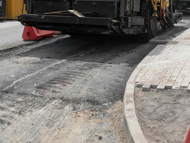 Pavimentadora aplicando asfalto em via de loteamento