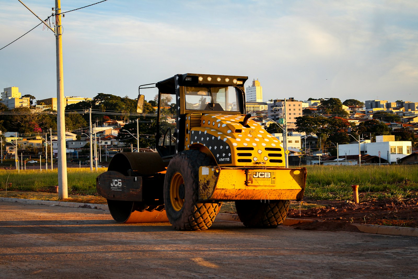 Rolo compactador amarelo compactando via